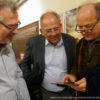 Bild von drei Männern die auf ein Smartphone schauen