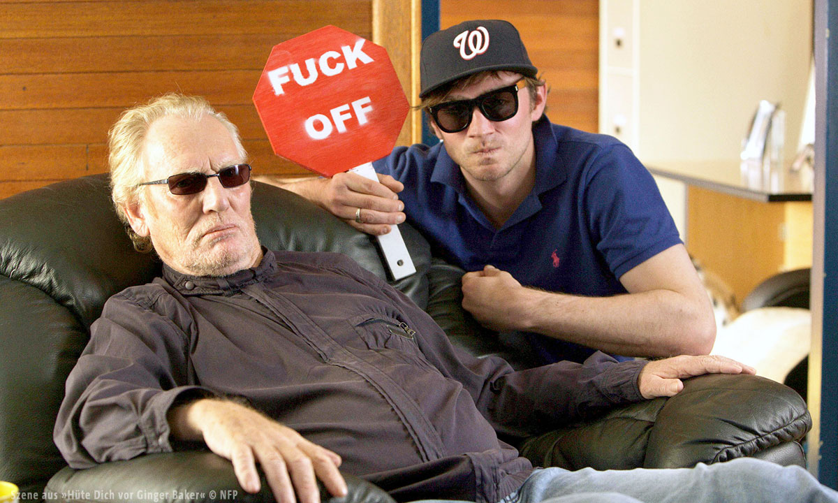Bild zweier Männer mit Sonnenbrille die ein Schild mit der Aufschrift "Fuck off" halten