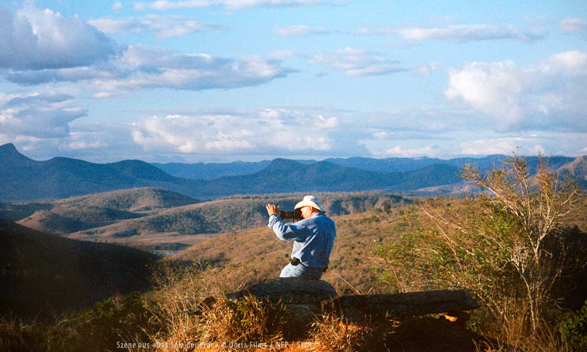 Bild eines Fotografen in einer Berglandschaft zwischen Gräsern