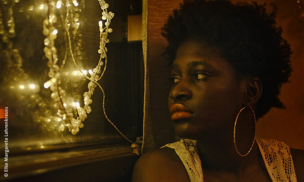 Filmszene aus "Lovemobil": Eine schwarze Frau blickt durch ein Fenster