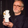 Festivallleiter Christoph Terhechte hält Goldene Taube beim DOK Leipzig © Susann Jehnichen
