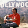 Eugen Cicero sitzend in der Landschaft, hinter ihm sieht man das Hollywood-Sign (Foto: Latemarfilm/Angelika E. Meier)